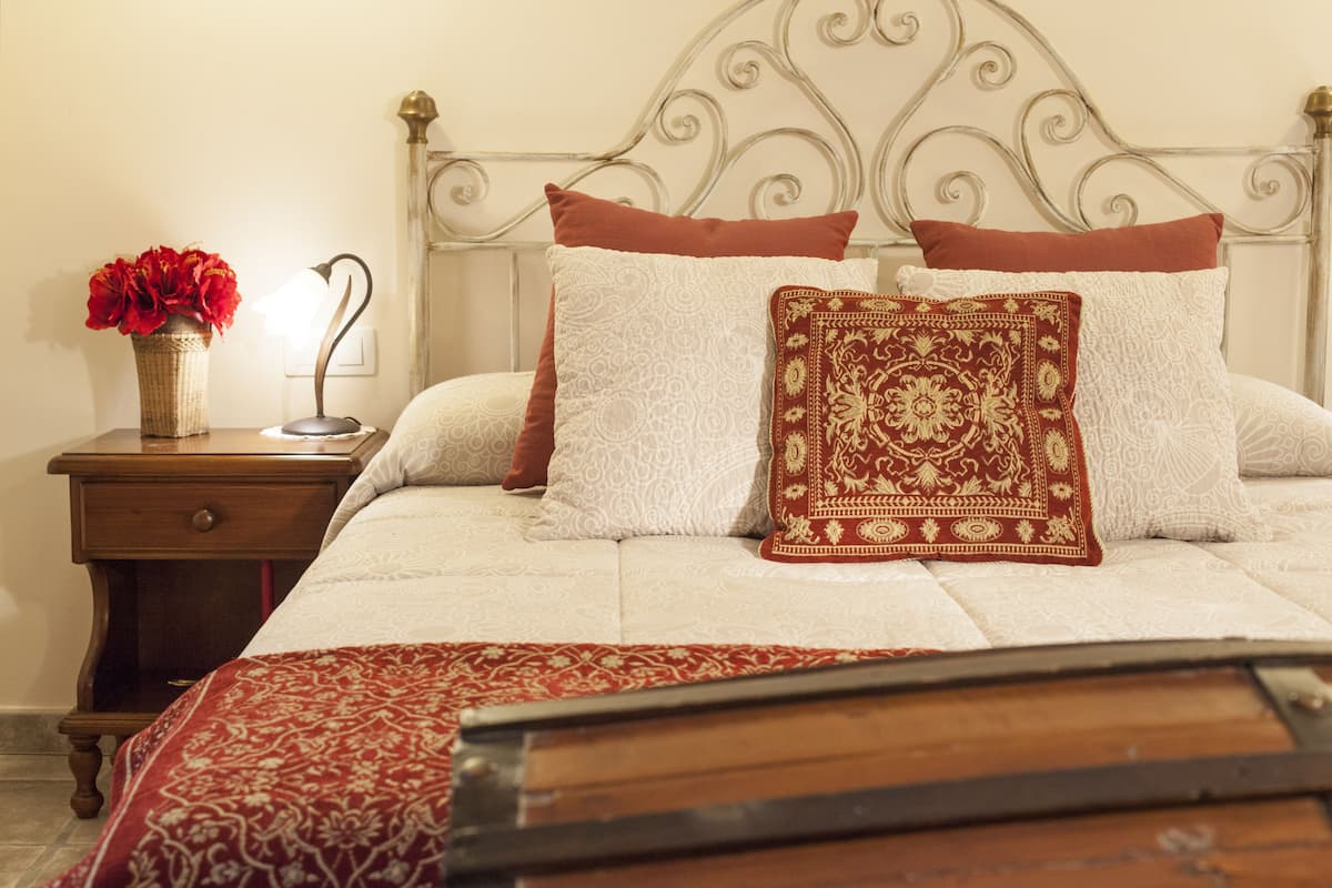 A neatly made bed with patterned pillows and a red throw blanket.