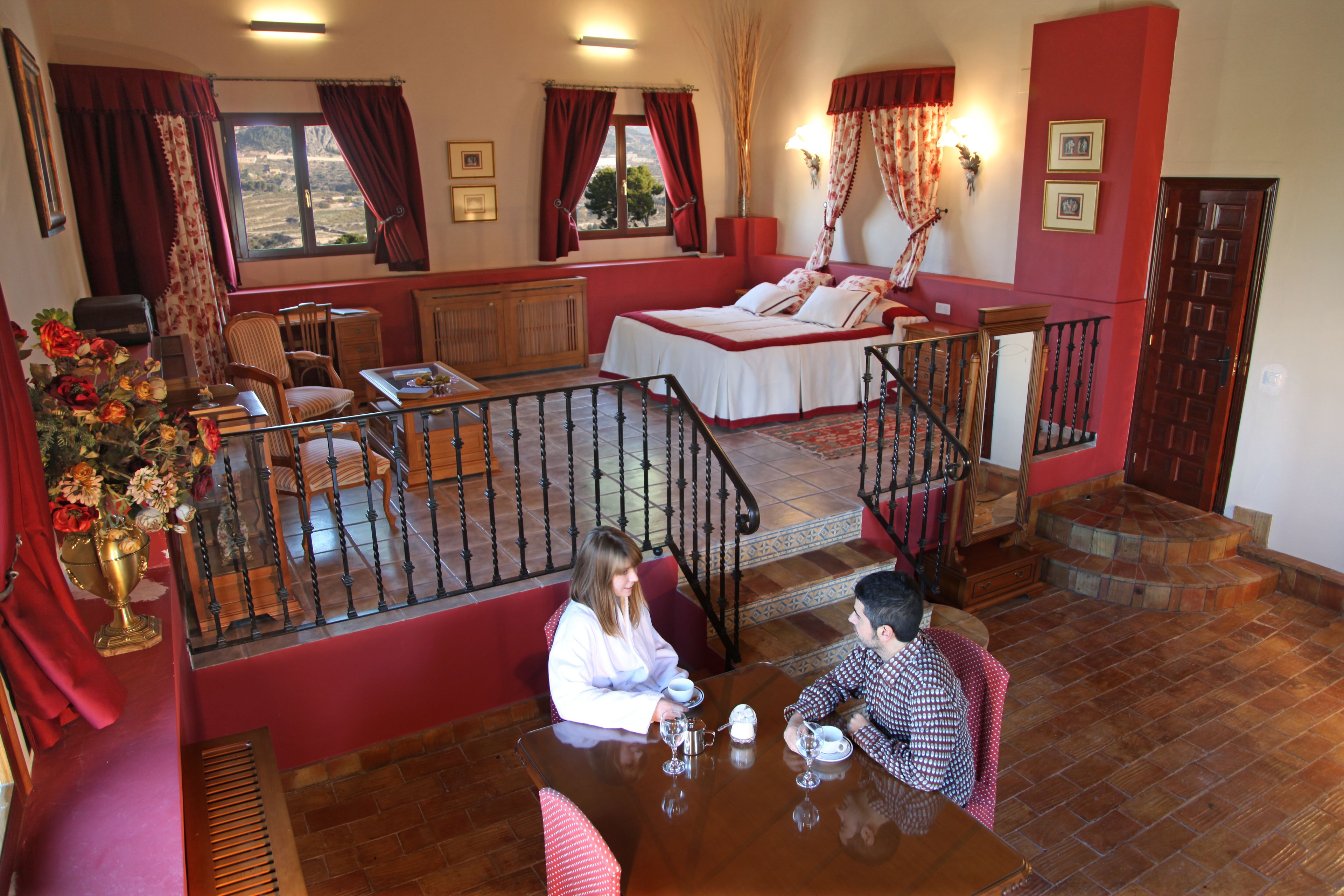 Ein Hotelzimmer mit Balkon, einem Bett, einem Esstisch und einer Treppe.