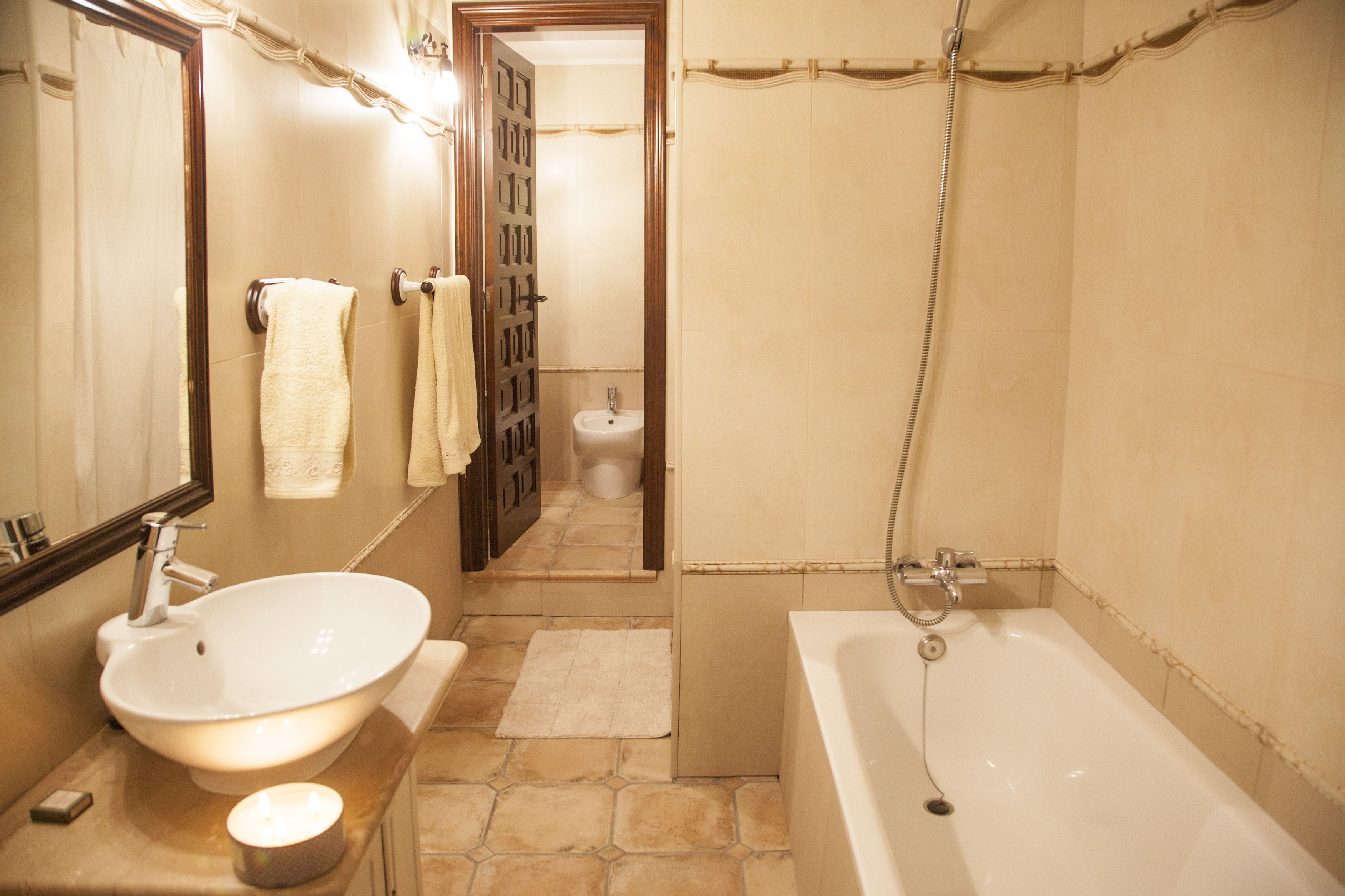 A bathroom with a sink, mirror, towel rack, shower, and toilet.