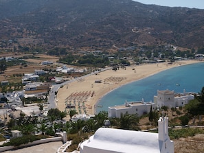 A coastal town with white buildings, a beach, and a mountainous backdrop. - Aegeon Hotel (Ios)