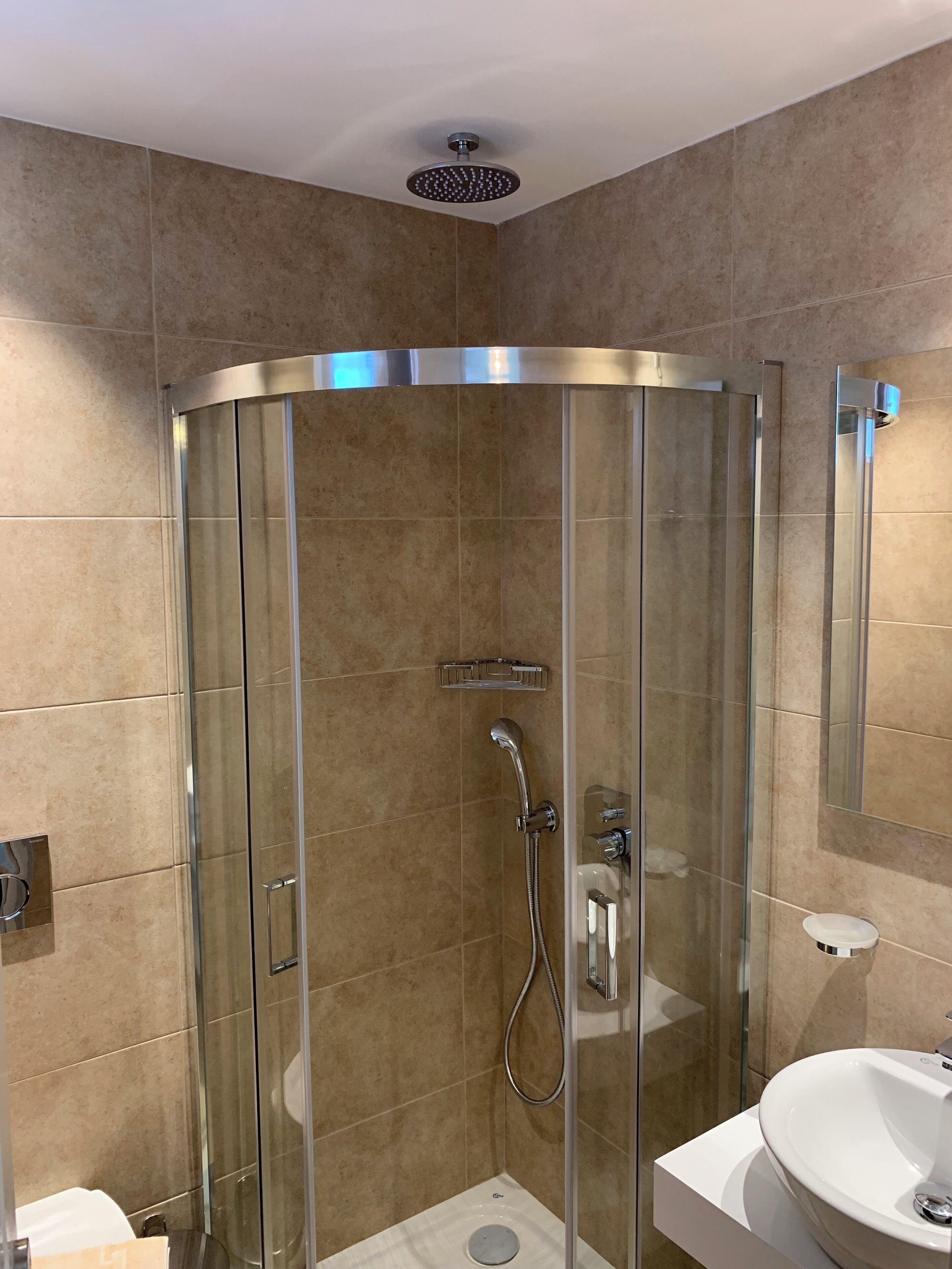 A modern bathroom with a glass-enclosed shower, a white sink, and a mirror.