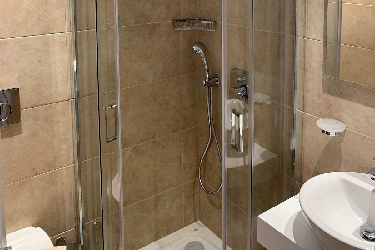 A modern bathroom with a glass-enclosed shower, a white sink, and a mirror.
