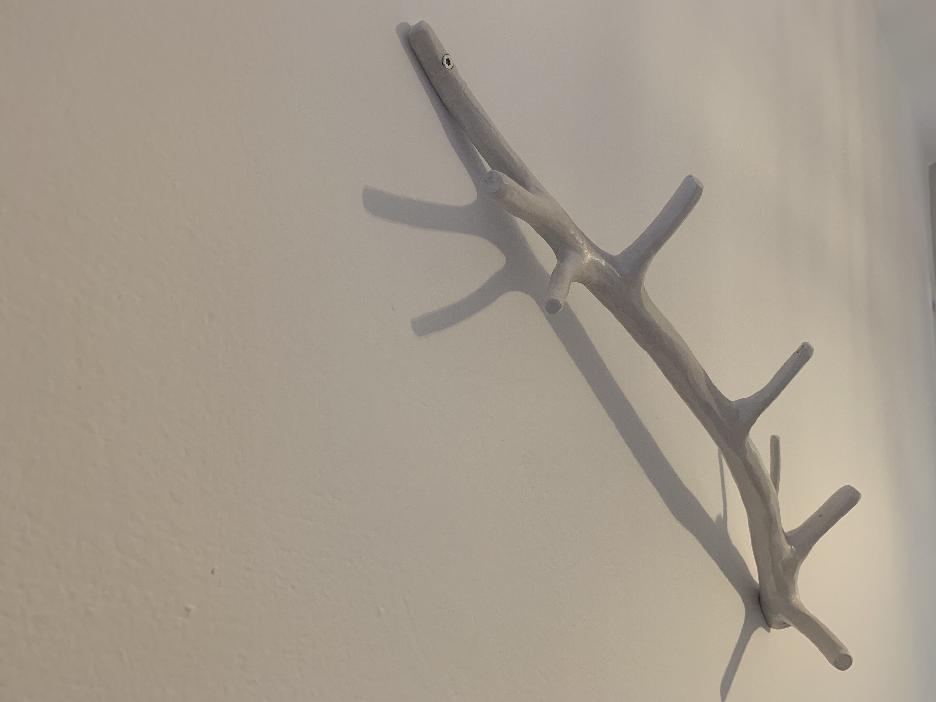A sculpture with a complex, abstract form mounted on a plain wall.