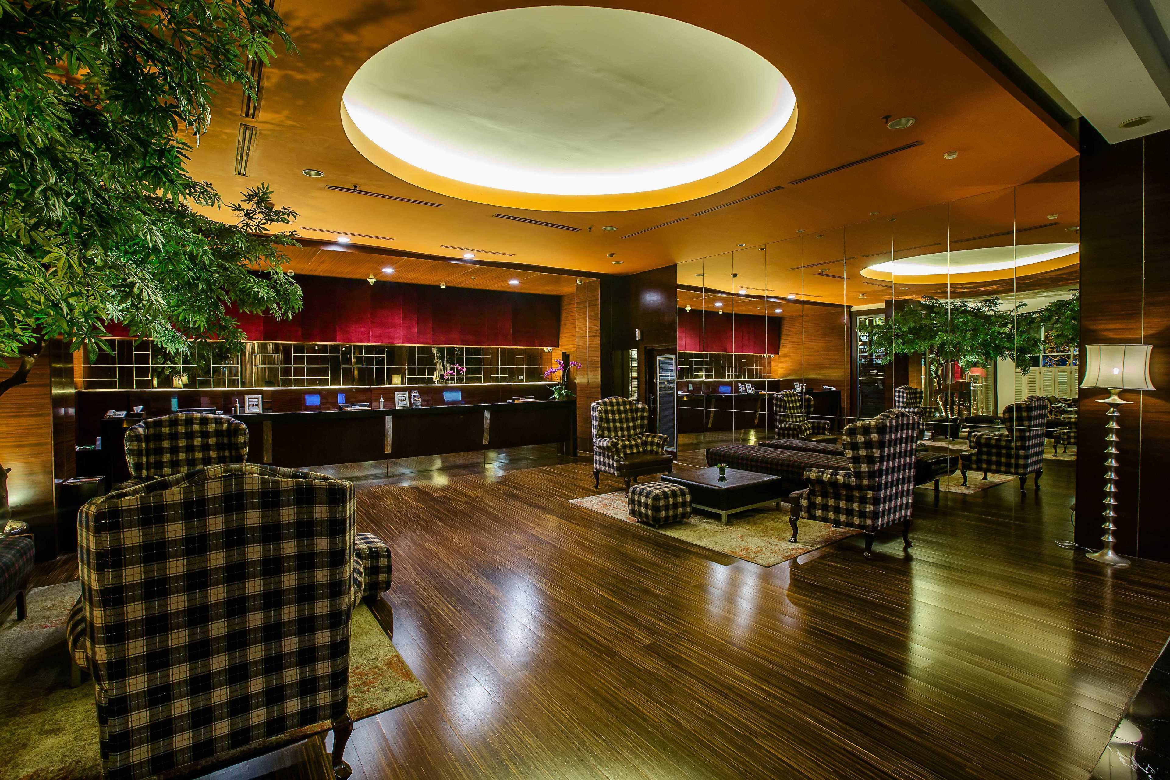 A lobby with a reception desk, check-in counters, and seating areas.