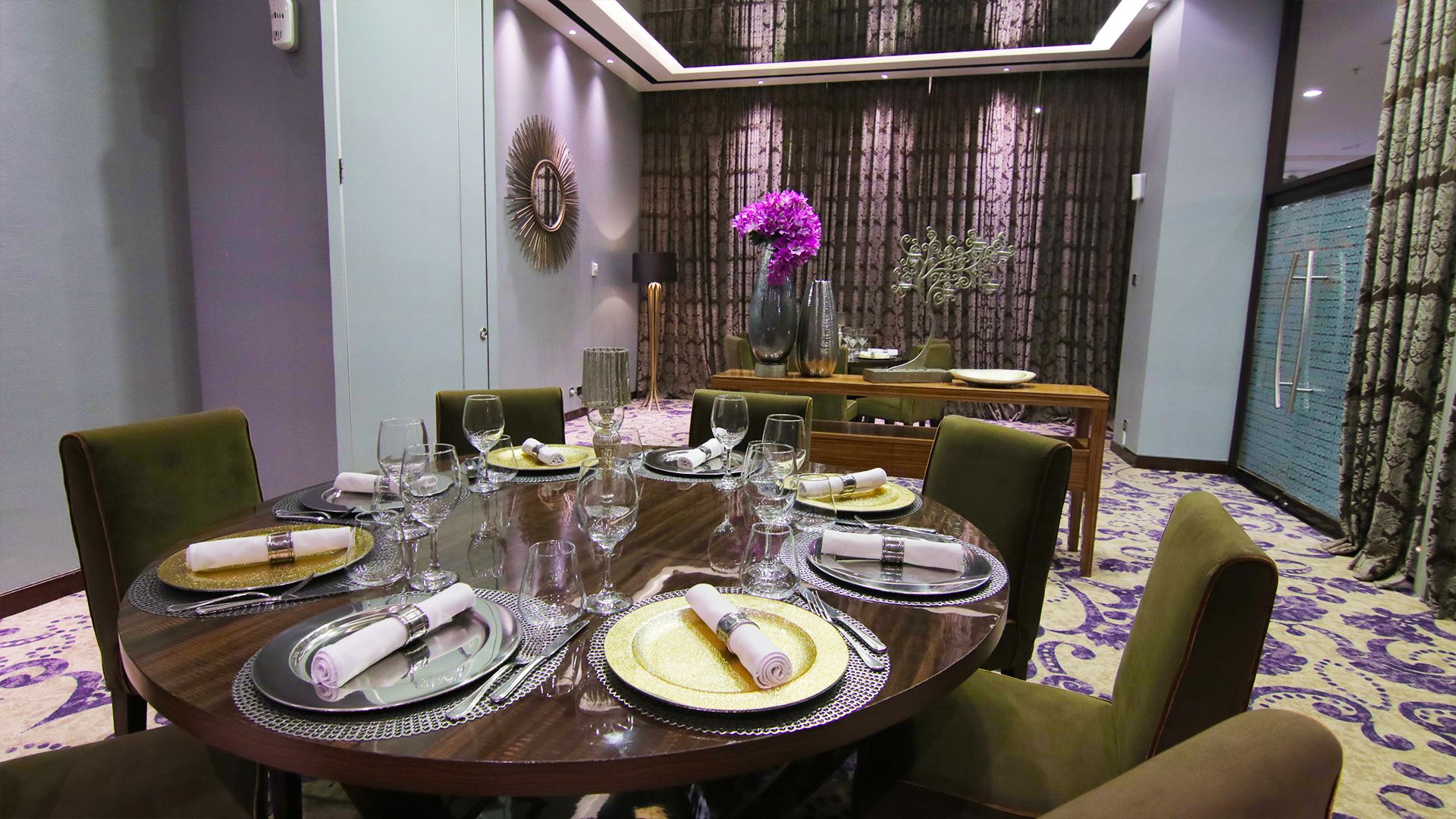 A dining area with a round table set for a meal, surrounded by chairs.