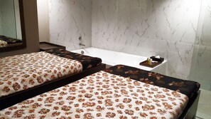 A hotel room with two beds, a bathtub, and a small table with toiletries.