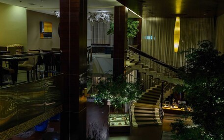A hotel lobby with a staircase, seating area, and a display case.
