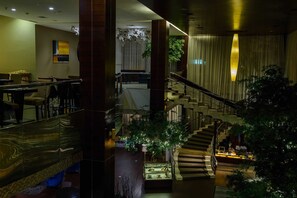 A hotel lobby with a staircase, seating area, and a display case. - The Arista Hotel (Palembang)