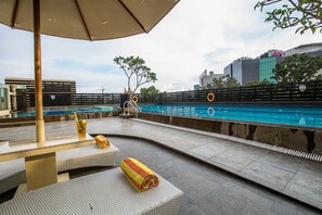 A rooftop pool area with lounge seating and a view of the city skyline.