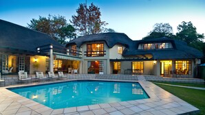 Una casa grande con piscina, múltiples ventanas y zonas de estar al aire libre.