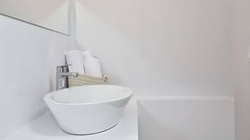Un baño blanco con un espejo grande, un lavabo blanco y dos toallas blancas colgadas en la pared.