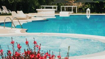 A swimming pool with lounge chairs and umbrellas.