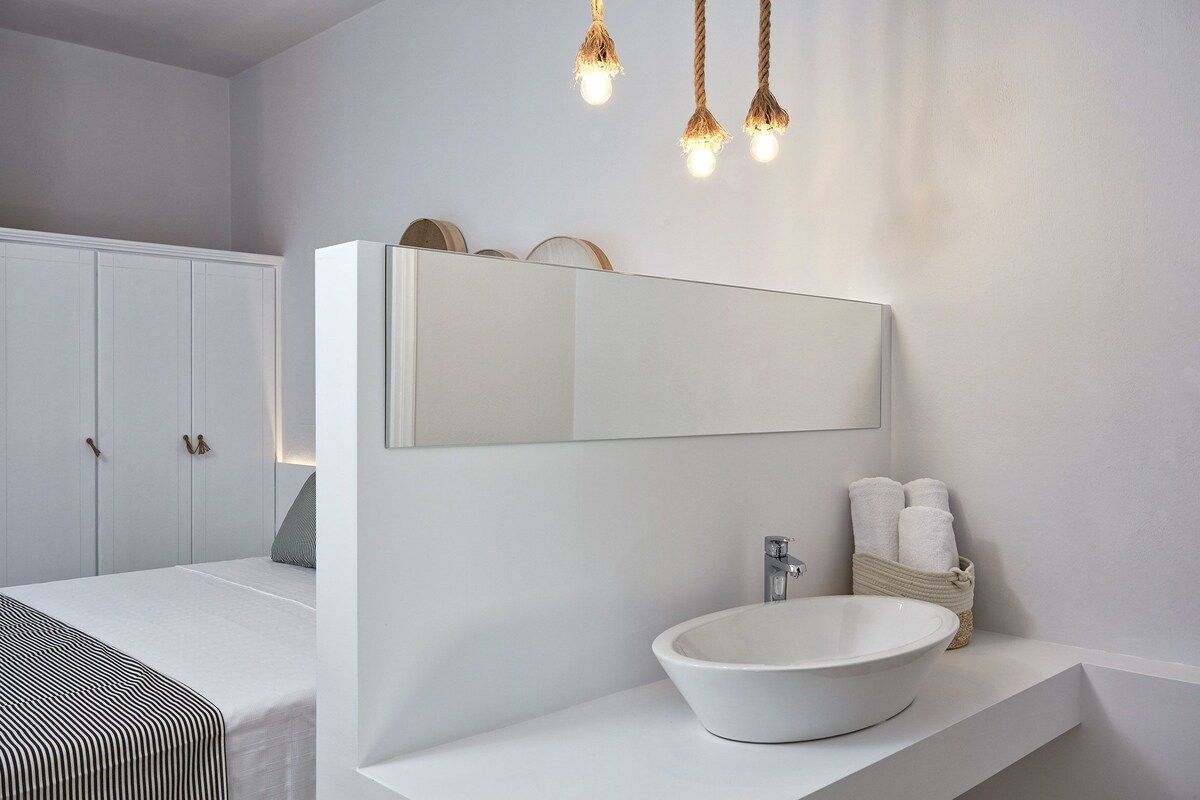 A modern bathroom with a large mirror, white sink, and hanging lights.