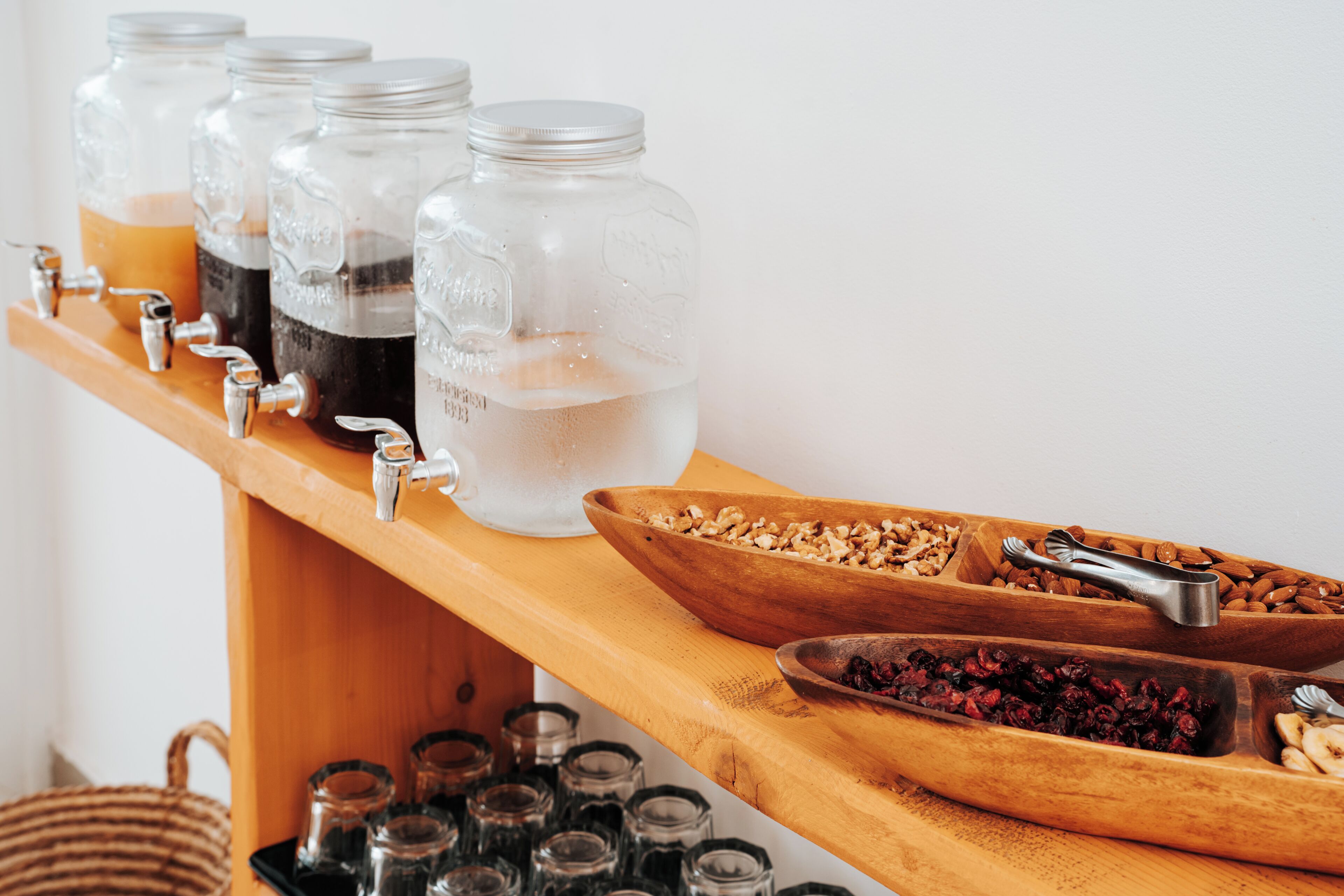 A beverage station with multiple jars and a bowl of nuts and dried fruits.