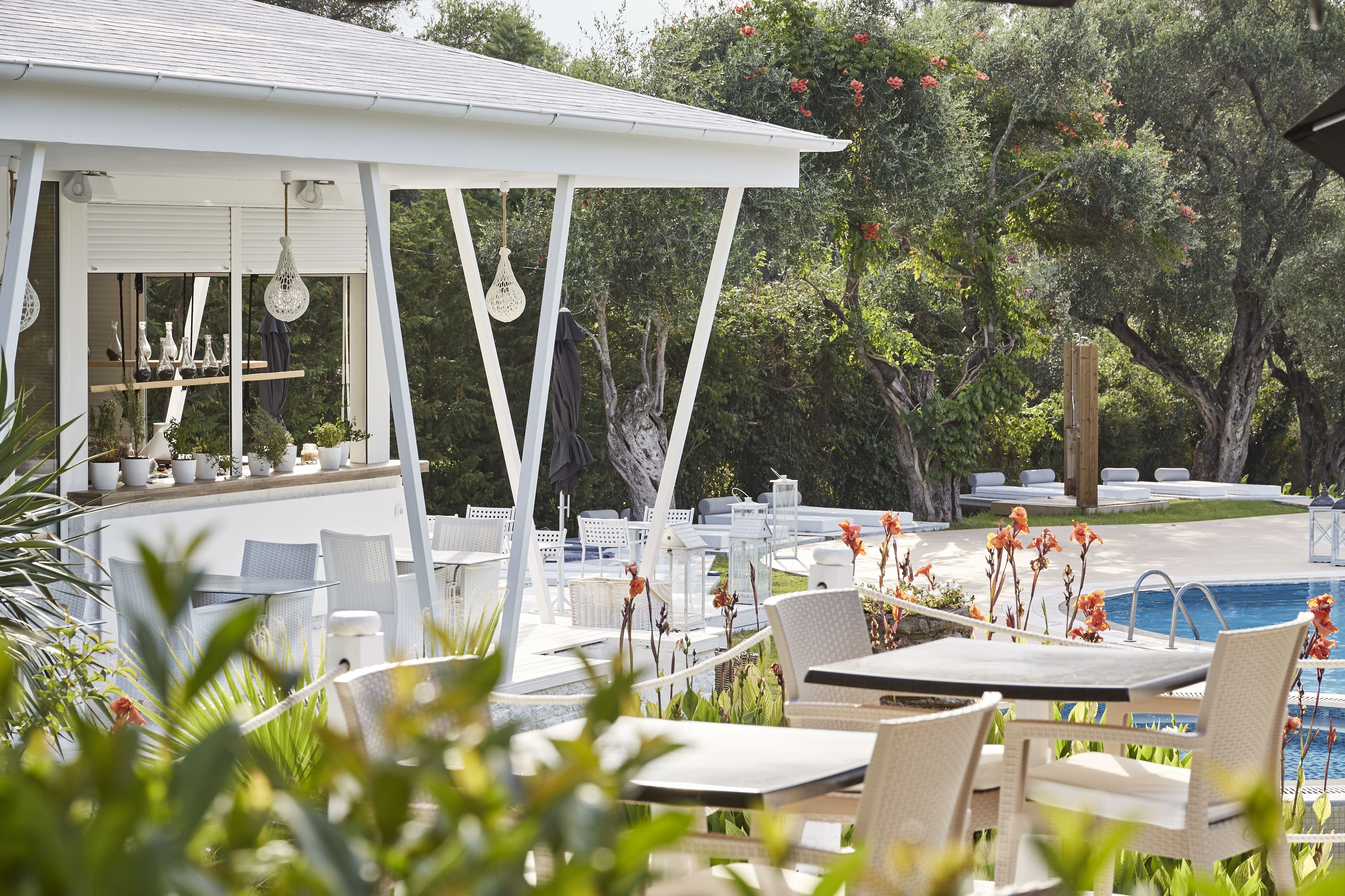 An outdoor seating area with tables and chairs, a pool, and a covered bar area with shelves of bottles.