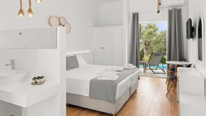 A modern hotel room with a large bed, a separate bathroom with a sink, a small table, and a chair. - Mr and Mrs White Corfu Couples Retreat Adults Only (Corfu)