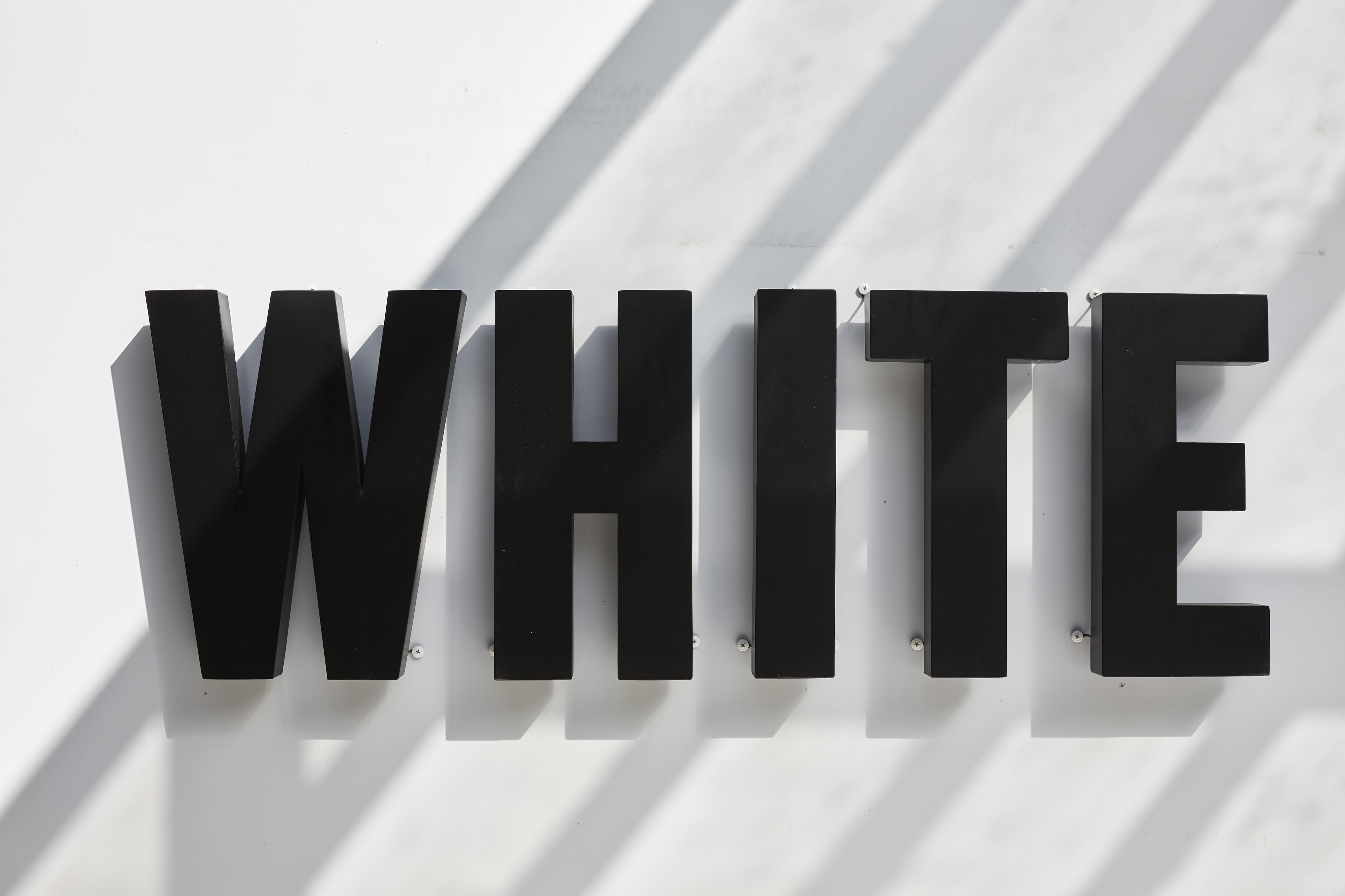 A wall-mounted sign with the word "WHITE" in capital letters.