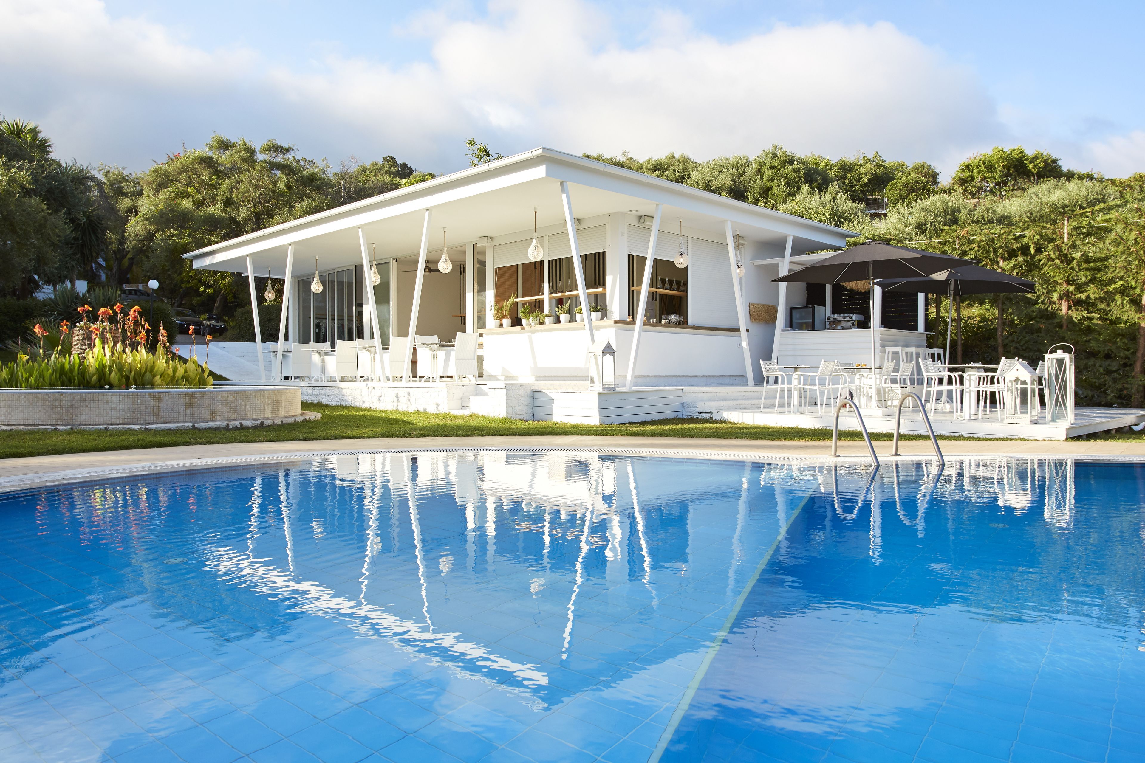 Un área moderna junto a la piscina con una zona de estar cubierta y una pileta.