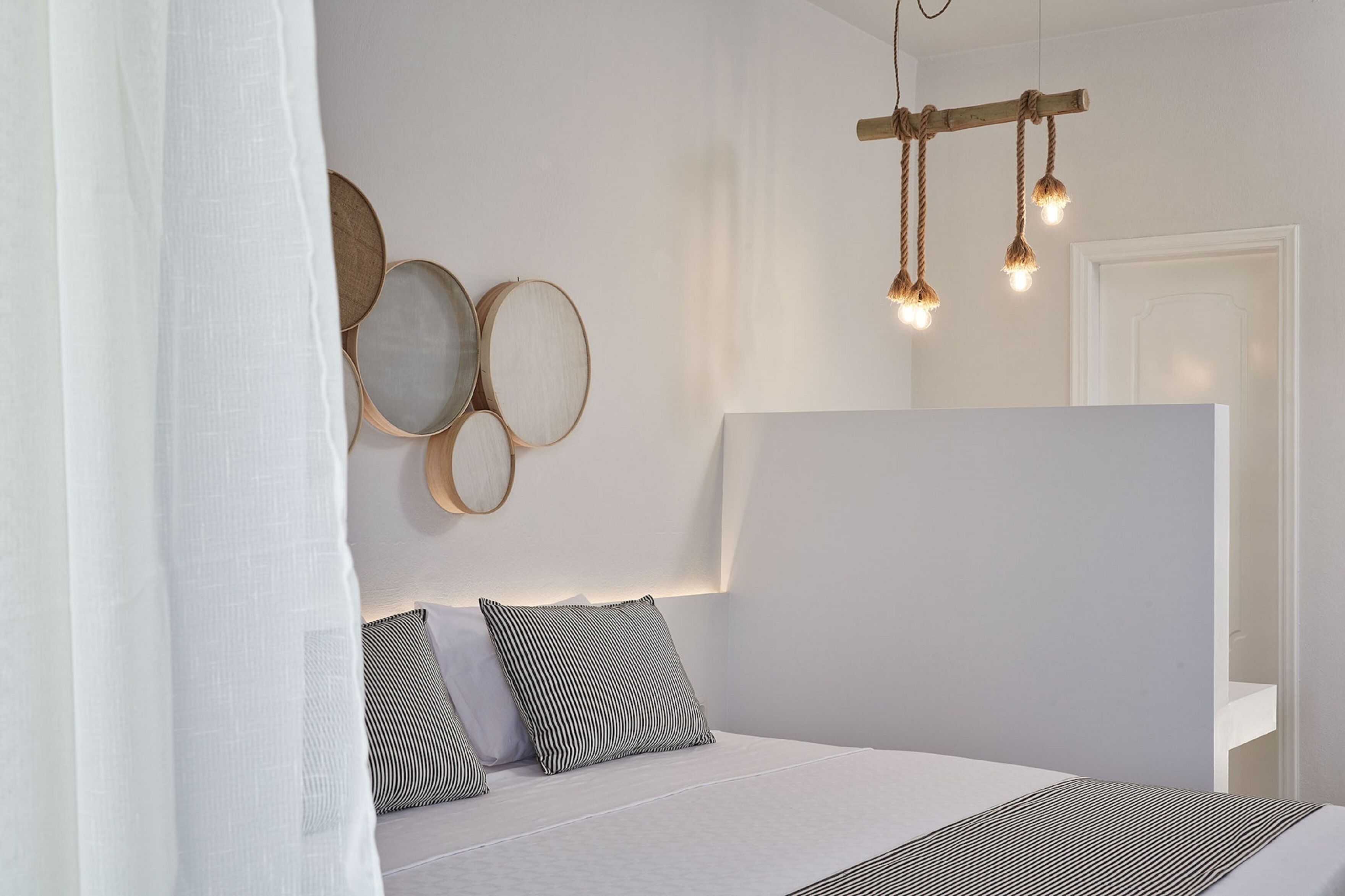 Un dormitorio moderno con una cama grande, una mesita de noche y una lámpara fijada a la pared.