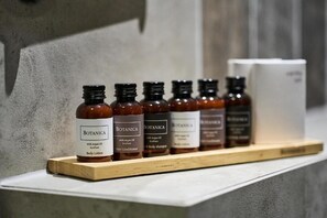 Een plank met zes flessen Botanica-producten, waaronder bodylotion en haarconditioner, op een houten plateau.