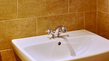 A bathroom with a white sink, a mirror with a circular light, and beige tiled walls.