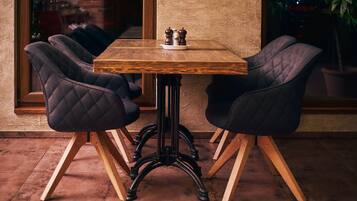 A wooden table with two upholstered chairs, a salt and pepper set, and a potted plant.