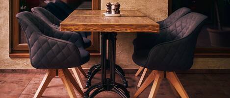 A wooden table with two upholstered chairs, a salt and pepper set, and a potted plant.