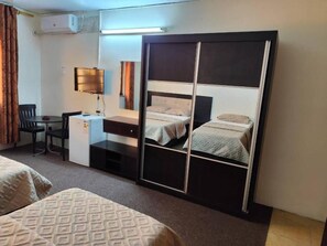 A hotel room with a bed, a desk, a chair, a TV, and a wardrobe. - Asia Hotel (Amman)