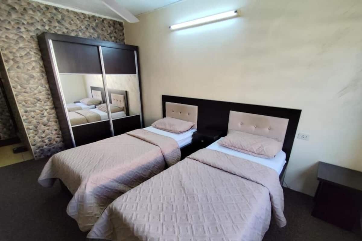 A bedroom with two beds, a large mirror, and a stone-patterned wall.