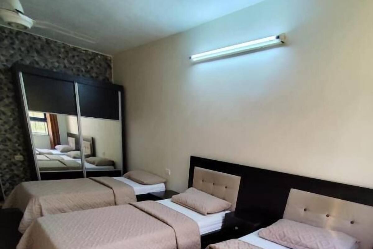 A hotel room with two beds, a large mirror, and a ceiling light.
