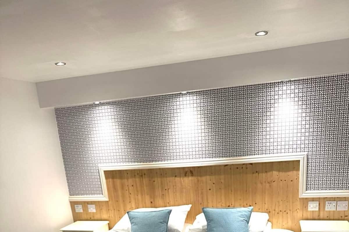 A hotel room with a large bed, two nightstands, a wooden headboard, and a patterned wall.