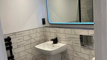 A modern bathroom with a white sink, a mirror with a blue light, and a toilet.