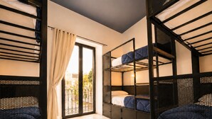Une chambre avec des lits superposés, une porte-fenêtre coulissante et un sol carrelé.