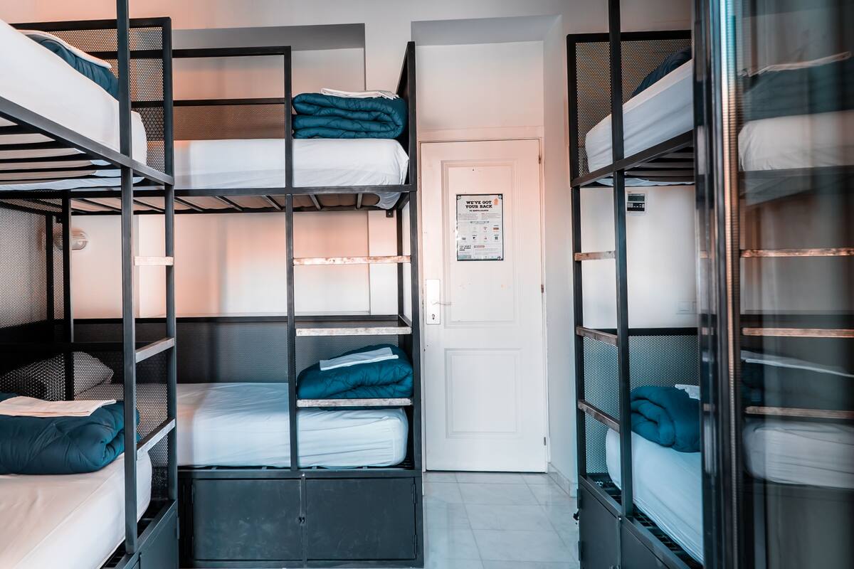 A room with bunk beds, a door, and a notice on the wall.