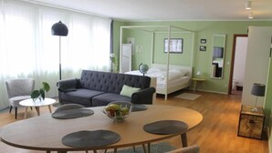 Een moderne hotelkamer met een ronde eettafel, een bank, een bed en een klein bijzettafeltje.