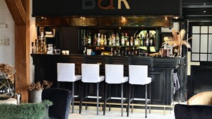 A bar with a black counter, white bar stools, and a variety of bottles. - Hostellerie Ten Lande (Beernem)