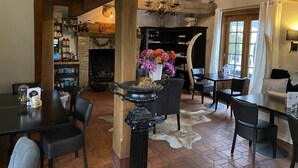 A cozy dining area with a fireplace, a chandelier, and a rustic stone wall. - Hostellerie Ten Lande (Beernem)