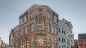 A corner building with a brick facade, multiple windows, and a visible parking sign. - Place2stay in Ghent (Ghent)