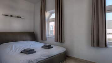 Una habitación de hotel moderna con una cama grande, un cabecero y una ventana con cortinas.