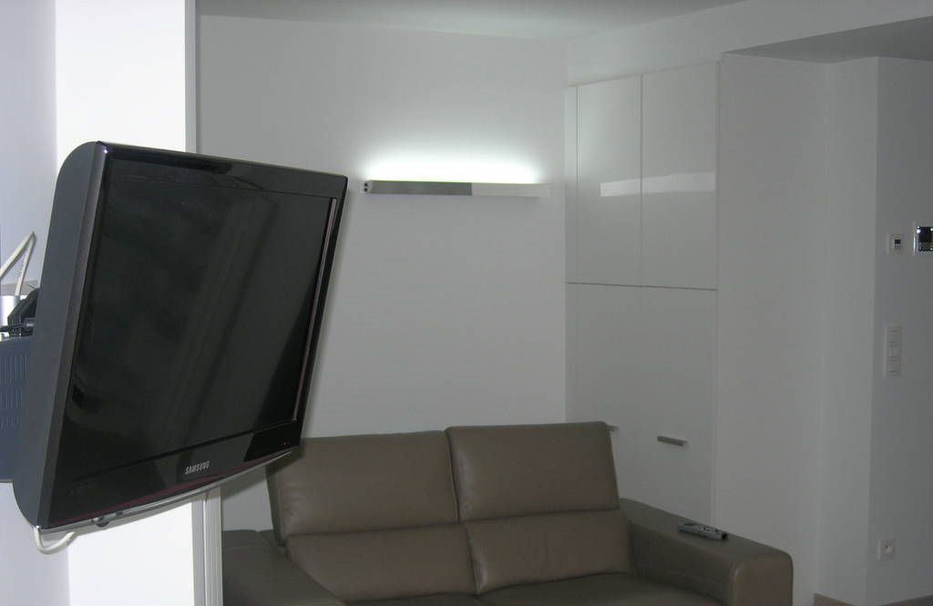 Une pièce équipée d’un téléviseur à écran plat fixé au mur, d’un canapé et d’un meuble.