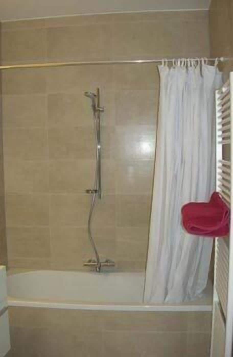 Une salle de bain avec une douche, une baignoire et un porte-serviettes.