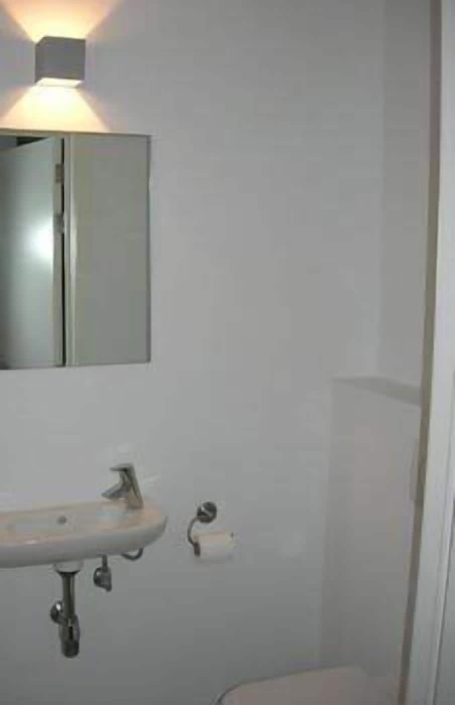 A bathroom with a white sink, a mirror, and a toilet.