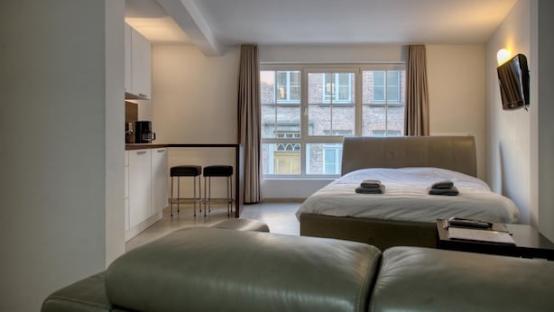 A modern hotel room with a large bed, a small kitchenette, and a view of the city. - Place2stay in Ghent (Ghent)