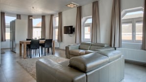A modern living room with a sofa, dining table, chairs, and a TV. - Place2stay in Ghent (Ghent)