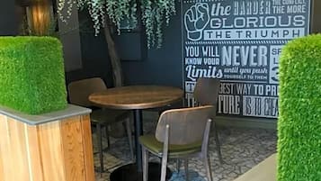A modern indoor seating area with a round wooden table, chairs, and a decorative wall with motivational quotes.