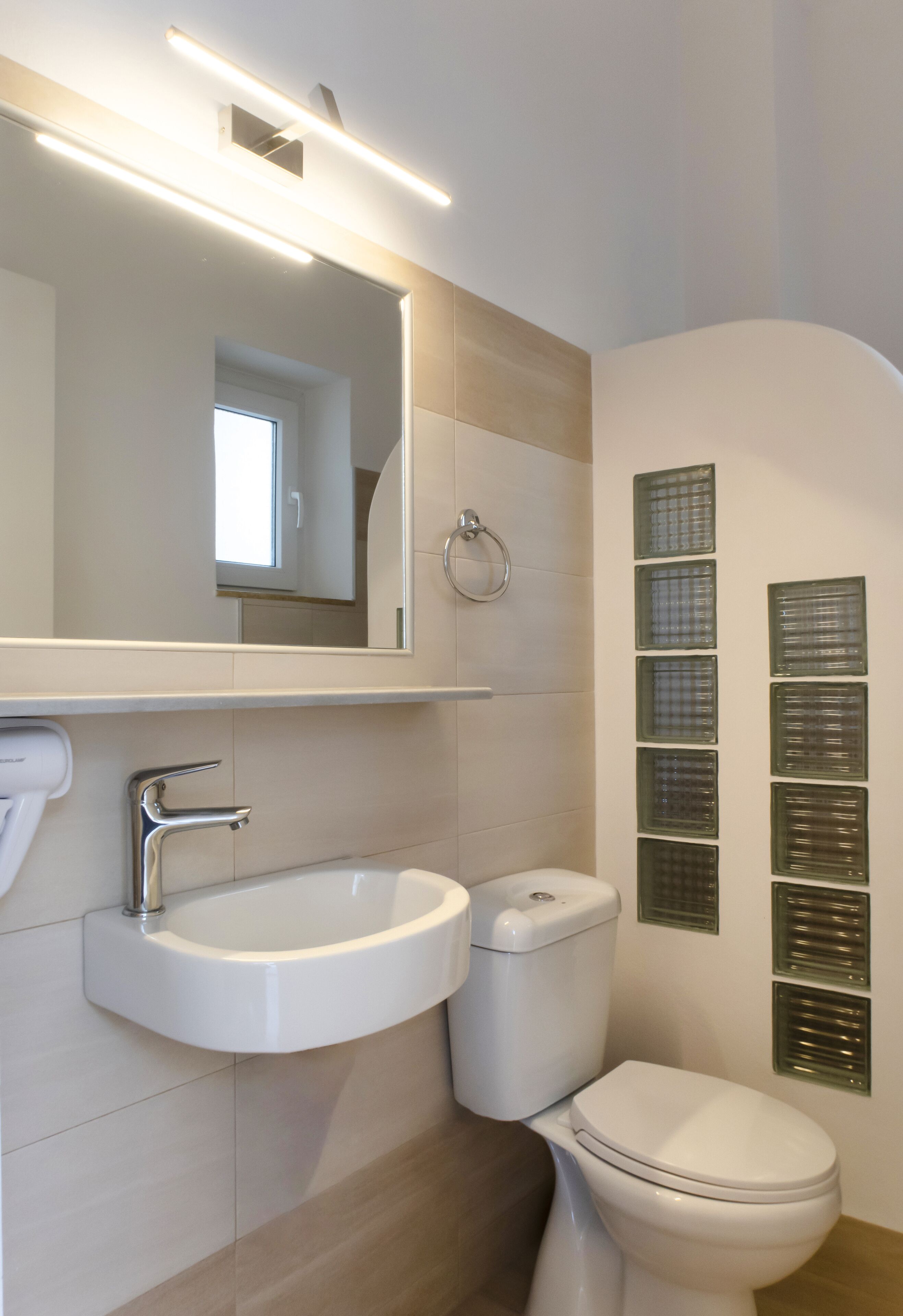 A modern bathroom with a white sink, a toilet, and a mirror.