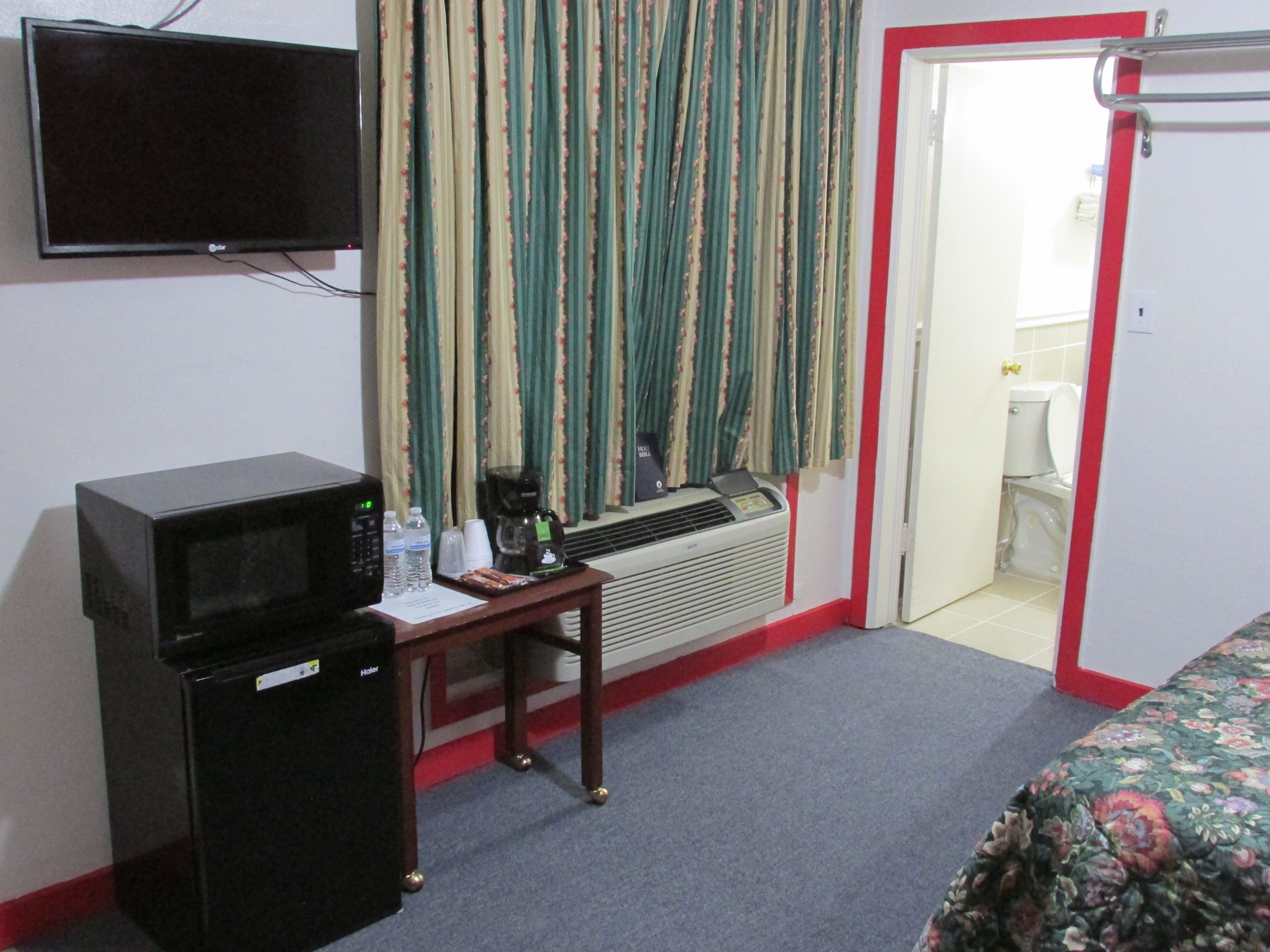 Une chambre d’hôtel équipée d’un bureau, d’un four à micro-ondes, d’un radiateur, d’une télévision et d’un lit.
