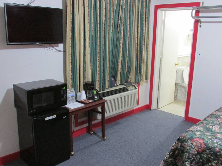 Une chambre d’hôtel équipée d’un bureau, d’un four à micro-ondes, d’un radiateur, d’une télévision et d’un lit.