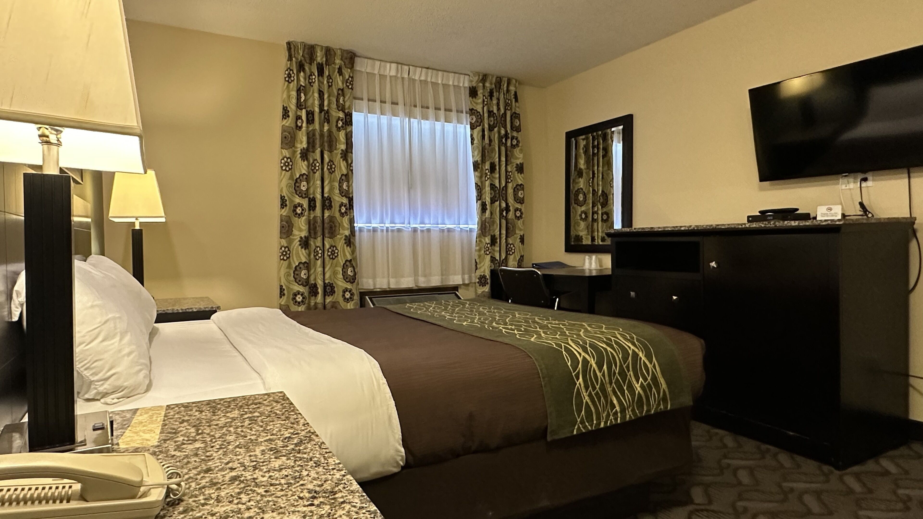 Una habitación de hotel con cama, escritorio, televisor y teléfono.