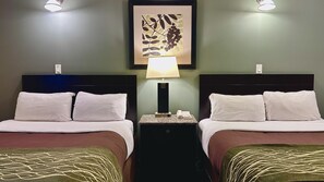 A hotel room with two beds, a nightstand with a lamp, a framed artwork on the wall, and a telephone.